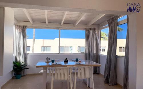 a dining room with a table and chairs in front of a window at B-Rent Los Delfines Casa Nina in Corralejo