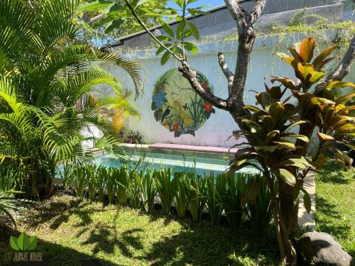 uma piscina num jardim com uma pintura na parede em The Jungle House em Canggu