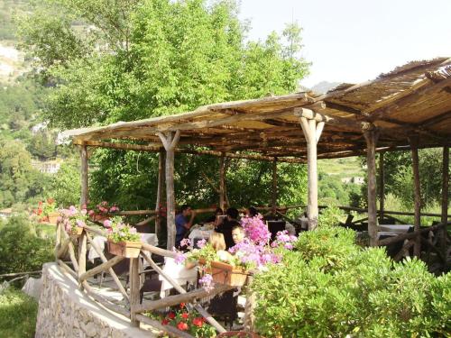 een groep mensen die onder een houten paviljoen met bloemen zitten bij Il Ducato Di Ravello in Ravello