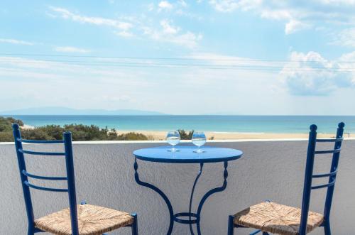 2 chaises et une table avec des verres à vin sur le balcon dans l'établissement Psili Ammos Studios, à Plage d'Aliko