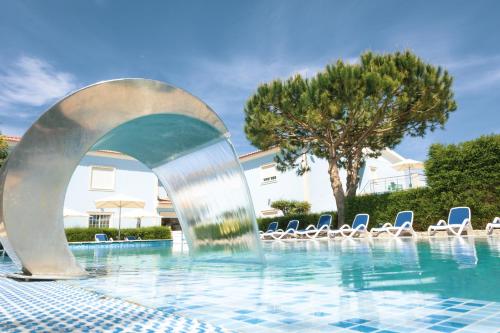 una fuente en una piscina con sillas en Hotel Neptuno, en Atouguia da Baleia