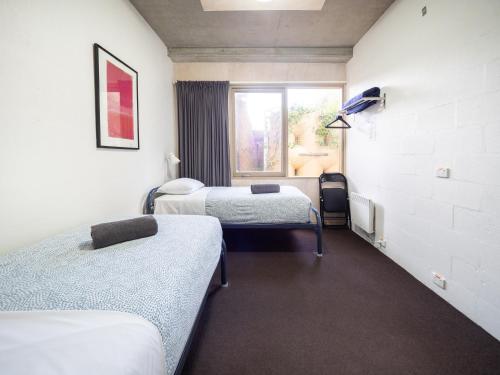 une chambre à l'hôpital avec trois lits et une fenêtre dans l'établissement YHA Apollo Bay Eco, à Apollo Bay