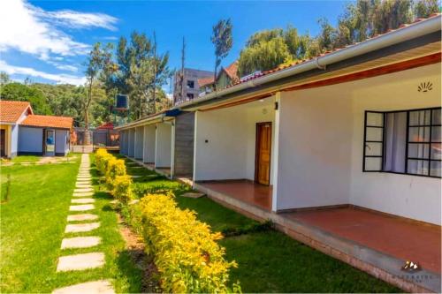 een huis met een groene tuin met gele bloemen bij Riverside Villas Nanyuki in Nanyuki