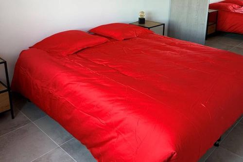 Una cama roja con una manta roja. en Appartement de standing piana, en Piana