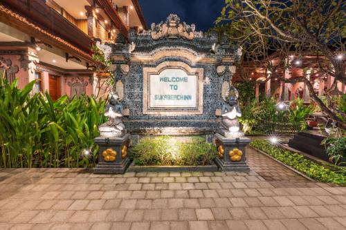 a sign in the middle of a garden at night at Suka Beach Inn in Kuta