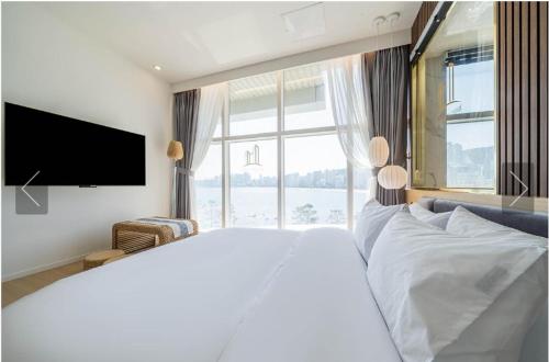 1 dormitorio con 1 cama blanca grande y ventana grande en De Homme Hotel, en Busan