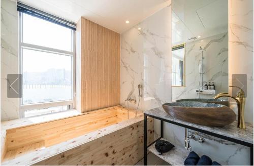 baño con lavabo de madera y ventana en De Homme Hotel, en Busan