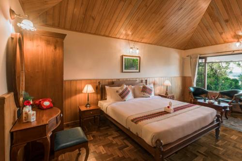 een slaapkamer met een bed, een bureau en stoelen bij Willow Hill by Nature Resorts in Ooty