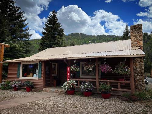 un petit bâtiment avec des plantes en pot devant lui dans l'établissement Three Bears Lodge, à Red River