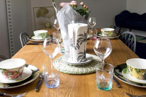 a wooden table with plates and wine glasses on it at Très Belle MAISON à Rennes St Jacques in Saint-Jacques-de-la-Lande