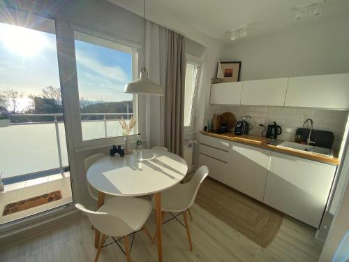 a kitchen with a white table and chairs and a window at Apartament Horizon in Gdynia