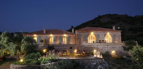 Cette grande maison en pierre est éclairée la nuit. dans l'établissement Katikies Manis, à Kardamyli