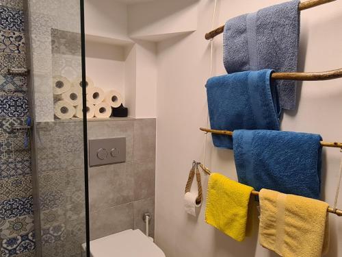 a bathroom with blue and yellow towels and a shower at Grisia 26 Apartment in Rovinj