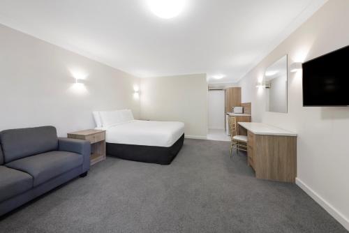 a hotel room with a bed and a couch and a tv at Elizabethan Lodge in Melbourne