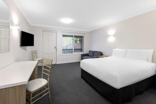 a hotel room with a large bed and a kitchen at Elizabethan Lodge in Melbourne