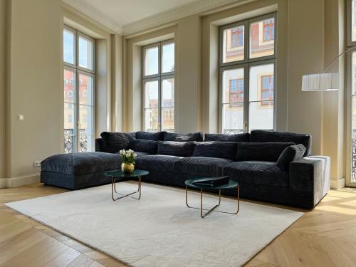 een woonkamer met een zwarte bank en 2 tafels bij Luxury Home / 3-Raum-Suite an der Frauenkirche / 4 in Dresden