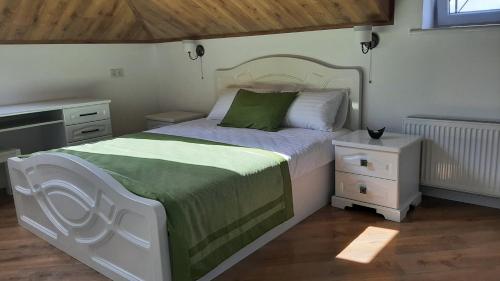 a bedroom with a bed with a green and white blanket at Апартаменти - Історія з вікна in Kamianets-Podilskyi