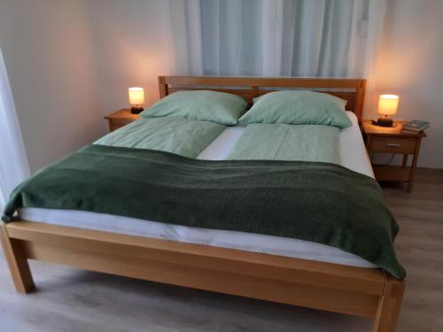 een bed met twee groene kussens en twee lampen bij Eisenstadt Apartments in Eisenstadt