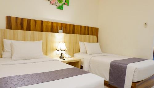 a hotel room with two beds and a table with two lamps at Vega Prime Hotel & Convention in Sorong