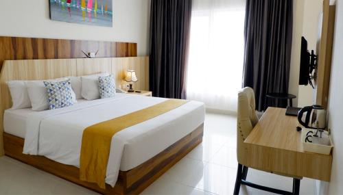 a hotel room with a bed and a desk and a bed sidx sidx at Vega Prime Hotel & Convention in Sorong