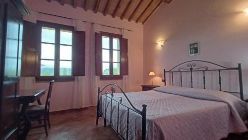 1 dormitorio con cama, mesa y ventanas en il Chiassetto Agriturismo No Kids, en Cascina