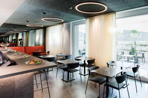 a restaurant with tables and chairs and a large window at Amedia Milan, Trademark Collection by Wyndham in Milan