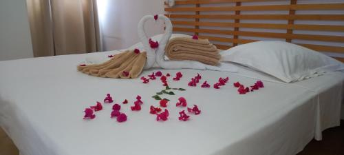 uma cama branca com flores cor-de-rosa e toalhas em Txada Hostel em Praia