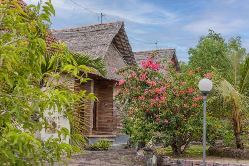 uma casa de tijolos com flores cor-de-rosa à frente. em Batang Golden Hills em Nusa Penida