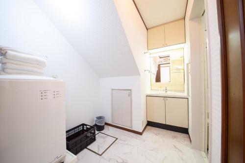 een kleine witte badkamer met een wastafel en een spiegel bij NY Cottage（コテージ） in Tokyo