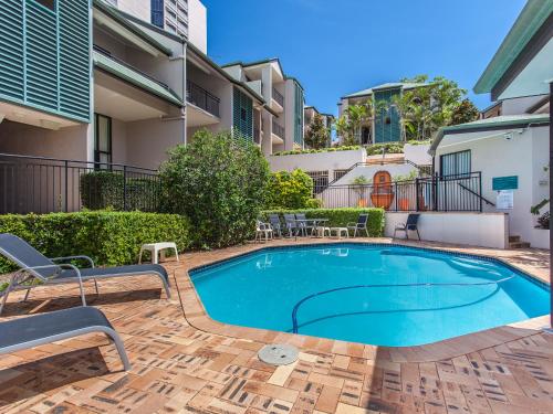 een zwembad op een binnenplaats met stoelen en een gebouw bij Spring Hill Mews Apartments in Brisbane