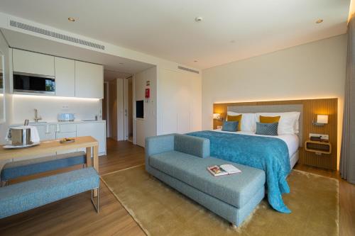 une chambre d'hôtel avec un lit et un canapé bleu dans l'établissement Martinhal Lisbon Oriente, à Lisbonne