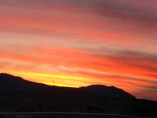 un tramonto con il sole che tramonta dietro una montagna di Death Valley/PrairieFire 3bd/2ba Home w/ Kitchen a Pahrump