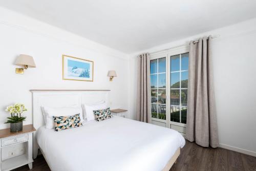 een witte slaapkamer met een groot bed en een raam bij Hôtel Beau Site - Cap d'Antibes in Antibes