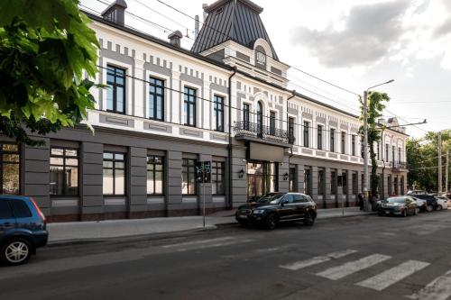 un gran edificio blanco con coches aparcados en una calle en Richmond Hotel en Chisináu