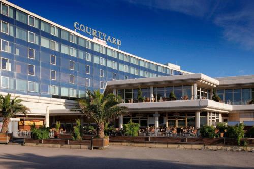 a hotel with palm trees in front of a building at Courtyard by Marriott Hannover Maschsee in Hannover