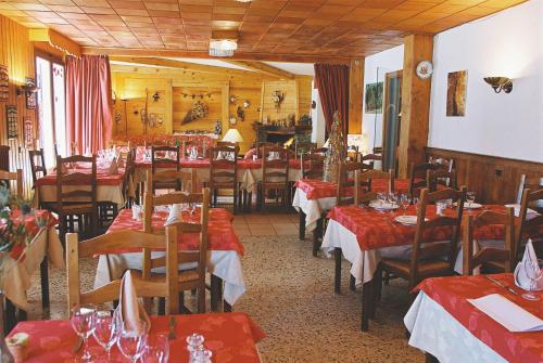 un restaurant avec des tables, des chaises et des nappes rouges dans l'établissement Edelweiss, à Samoëns