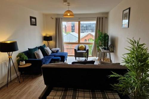 - un salon avec un canapé bleu et une grande fenêtre dans l'établissement Modern apartment, sleeps 6, Belfast city centre, à Belfast