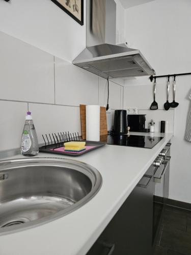 een witte keuken met een wastafel en een fornuis bij Gemütliche Wohnung in ruhigem Wohngebiet in Aschaffenburg