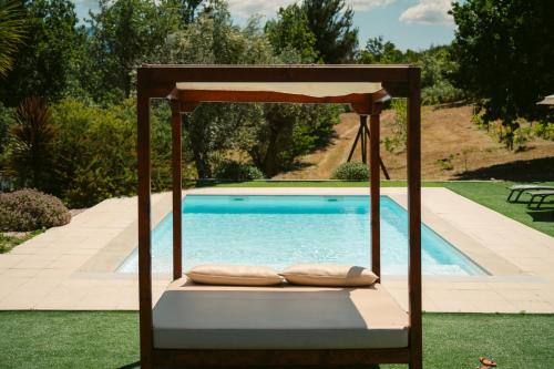 un letto a dondolo con cuscini accanto alla piscina di Pura - Home in Nature a Oliveira do Hospital