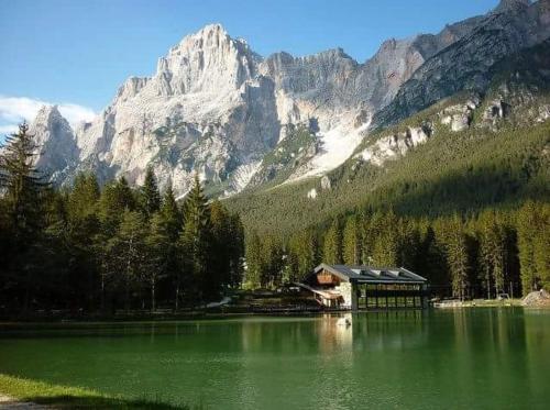 une maison sur un lac en face d'une montagne dans l'établissement Chalet Al Lago, à San Vito di Cadore