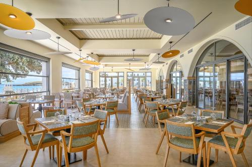 a restaurant with tables and chairs and windows at Creta Maris Resort in Hersonissos