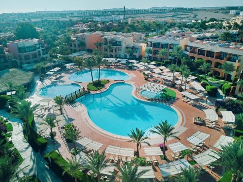 an aerial view of a resort pool with palm trees and buildings at Jaz Makadi Saraya Resort in Hurghada