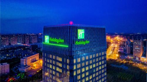 een hoog gebouw met een groen bord erop bij Holiday Inn Changchun Oriental Plaza, an IHG Hotel in Changchun