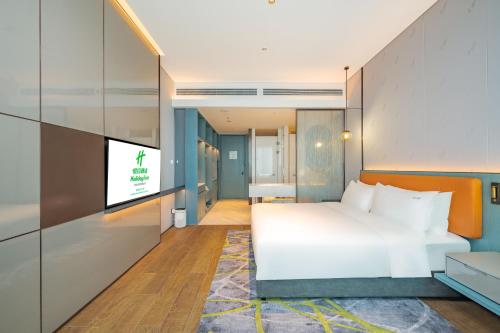 een slaapkamer met een bed en een flatscreen-tv bij Holiday Inn Changchun Oriental Plaza, an IHG Hotel in Changchun