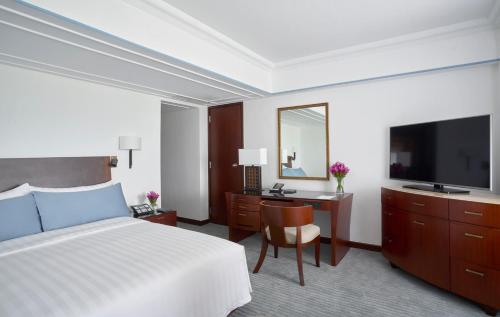 una camera d'albergo con letto e TV di The Peninsula Manila a Manila