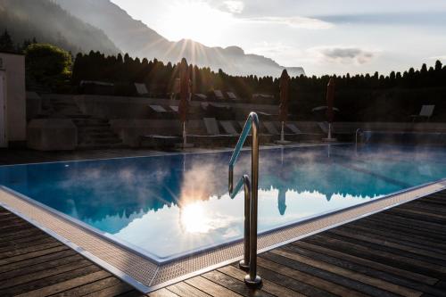 ein Pool mit der Sonne, die im Wasser reflektiert in der Unterkunft elaya hotel steinplatte ehemals KUHOTEL by Rilano in Waidring