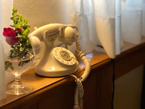 a telephone on a table with a vase of flowers at Ameiserhof Guesthouse in Collalbo