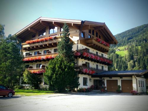 un grand immeuble avec des fleurs sur les balcons dans l'établissement Pension Dorferwirt, à Bramberg am Wildkogel