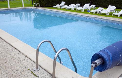 a swimming pool with chairs and a blue hose next to it at Kyriad Deauville - St Arnoult in Deauville