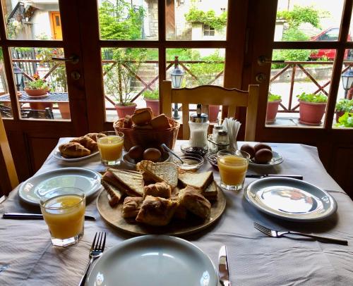 un tavolo con piatti di cibo e bicchieri di succo d'arancia di Apostolos Hotel a Metsovo